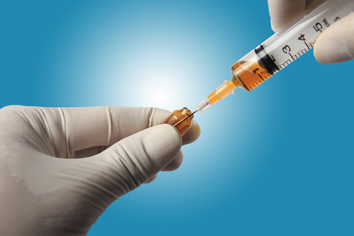 Syringe with a medicine in hands, isolated on blue